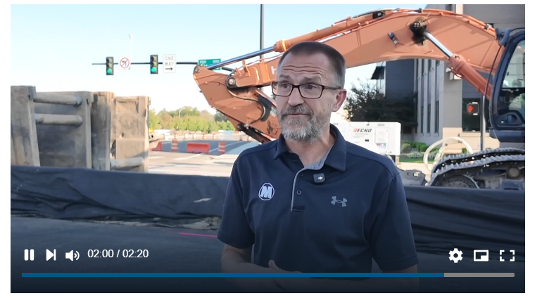 Michael Blood on camera at the Main Street closure, excavator and closed intersection behind him
